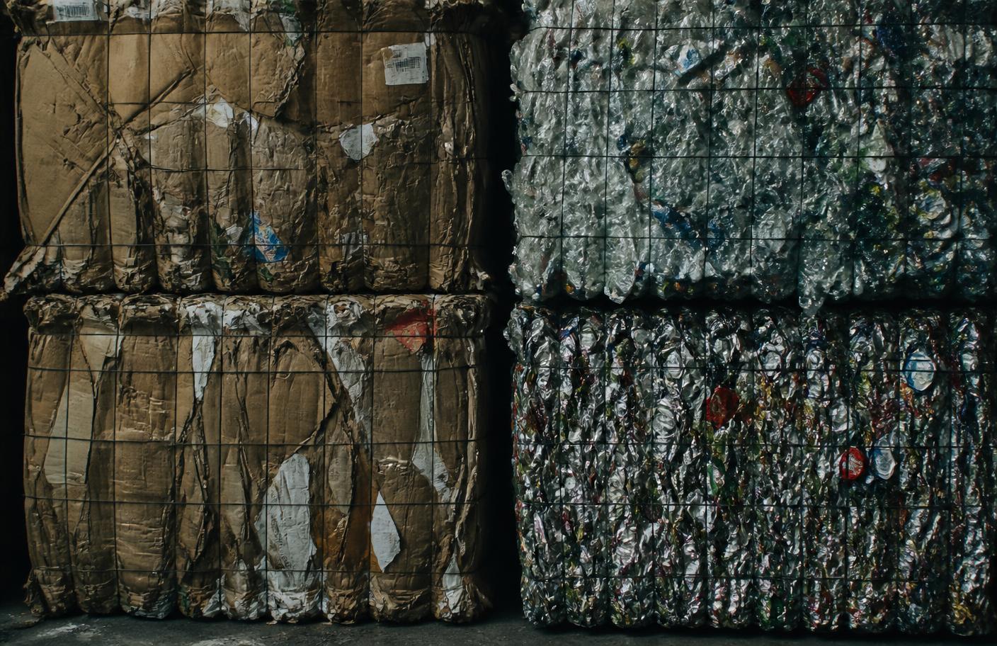Sorterede baller af pap, plast og metal stablet i en industrihal